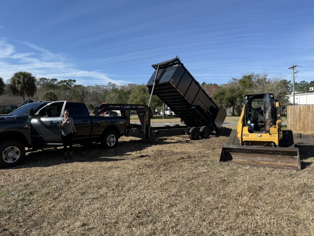 AGES Tree Service truck with dump trailer and CAT skid steer on job site in North Florida