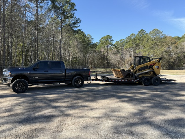 AGES Tree Service RAM truck hauling CAT skid steer on flatbed trailer in Jacksonville FL